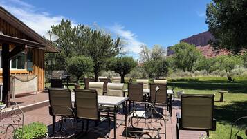 An outdoor patio with a wooden deck, outdoor furniture, and a view of the surrounding landscape.