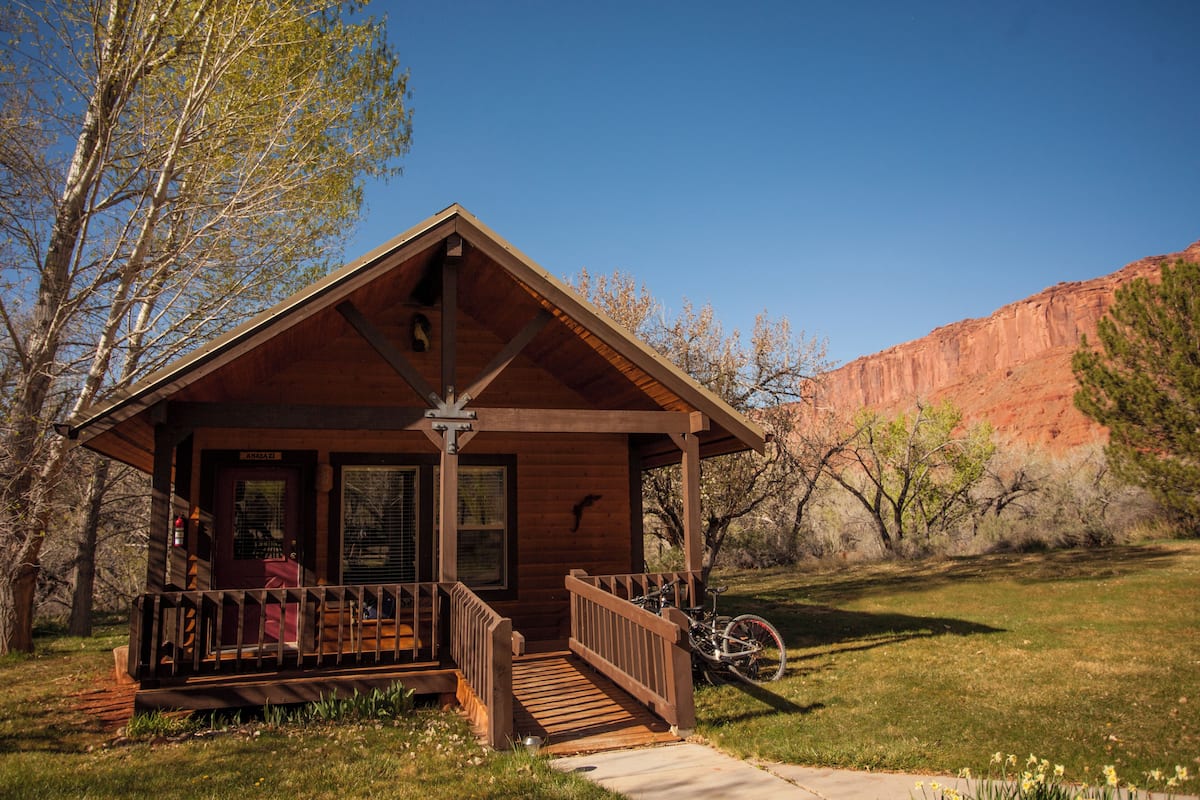 A wooden cabin with a porch, a bicycle, and a clear view of the surrounding landscape.