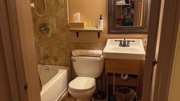 Une salle de bain équipée d’une baignoire, de toilettes, d’un lavabo et d’un miroir avec éclairage.