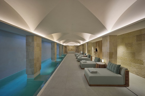 Uma área de spa com uma piscina extensa, assentos e paredes de pedra.