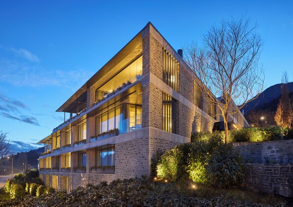 A modern building with a flat roof, large windows, and a stone facade.