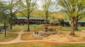 A lodge with a covered outdoor seating area, a stone fire pit, and a winding path. - Renovated King ADA Pet-Friendly room (Townsend)