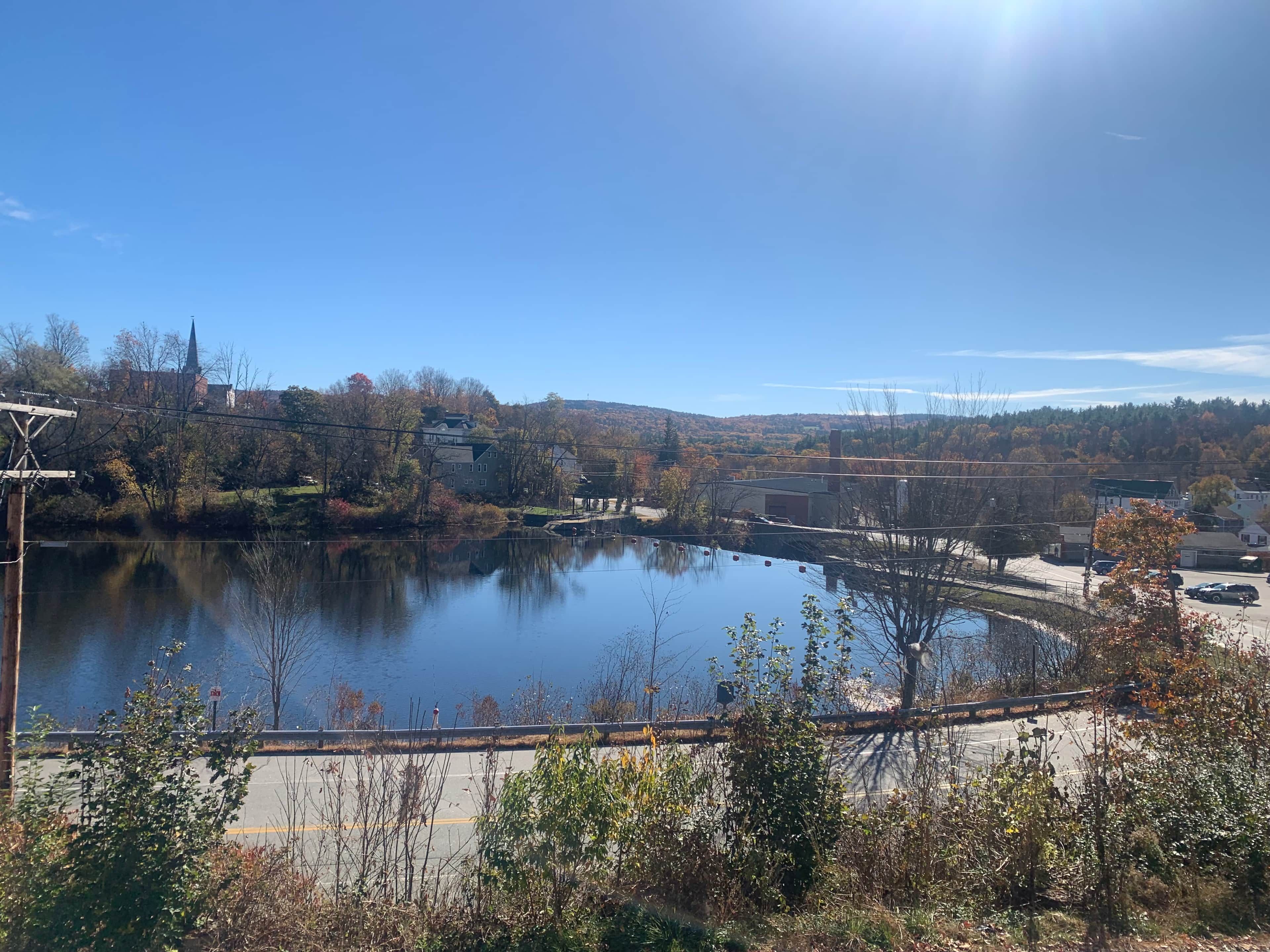 Un lac avec un pont, des bâtiments et des arbres en arrière-plan.