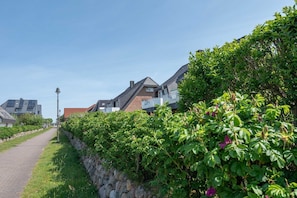 Eine Wohnstraße mit Häusern, einer Steinmauer und einem Fußweg.