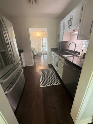A kitchen with white cabinets, stainless steel appliances, and a patterned rug. - Highland Park Beauty Walkable to Rojo and Parks! (Birmingham)