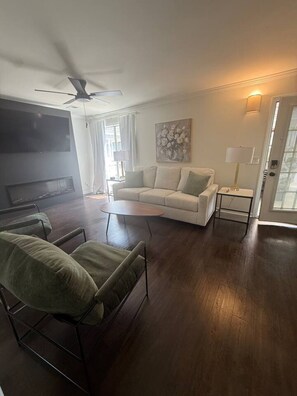 Ein Wohnzimmer mit Sofa, Couchtisch, Fernseher und Deckenventilator.