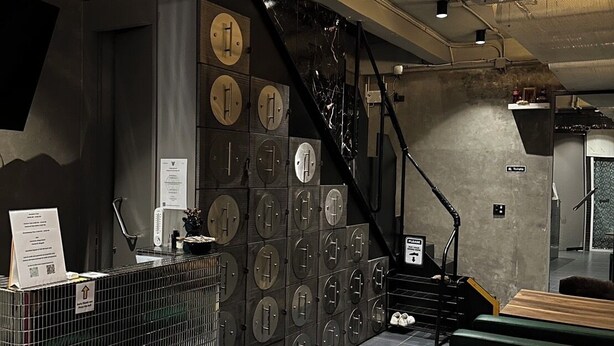 A modern interior with a metal counter, multiple lockers, and a staircase. - Stingy Hostel (Bangkok)