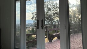 Vista a través de un ventanal con una terraza de madera y un banco.