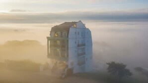 Un edificio de varios pisos con una imponente torre de reloj, rodeado de niebla.