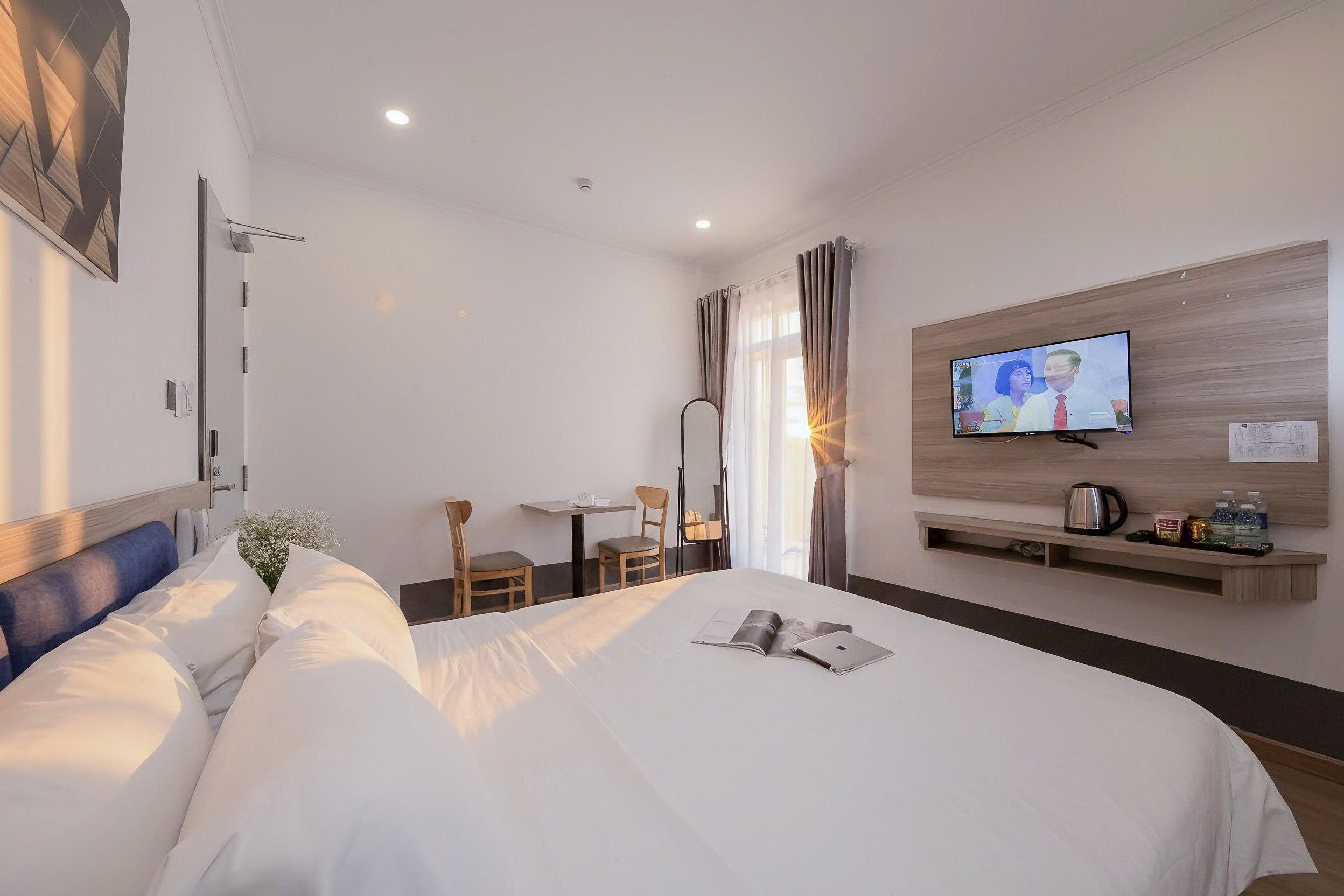 Ett hotellrum med en säng, en tv, ett skrivbord och en stol.