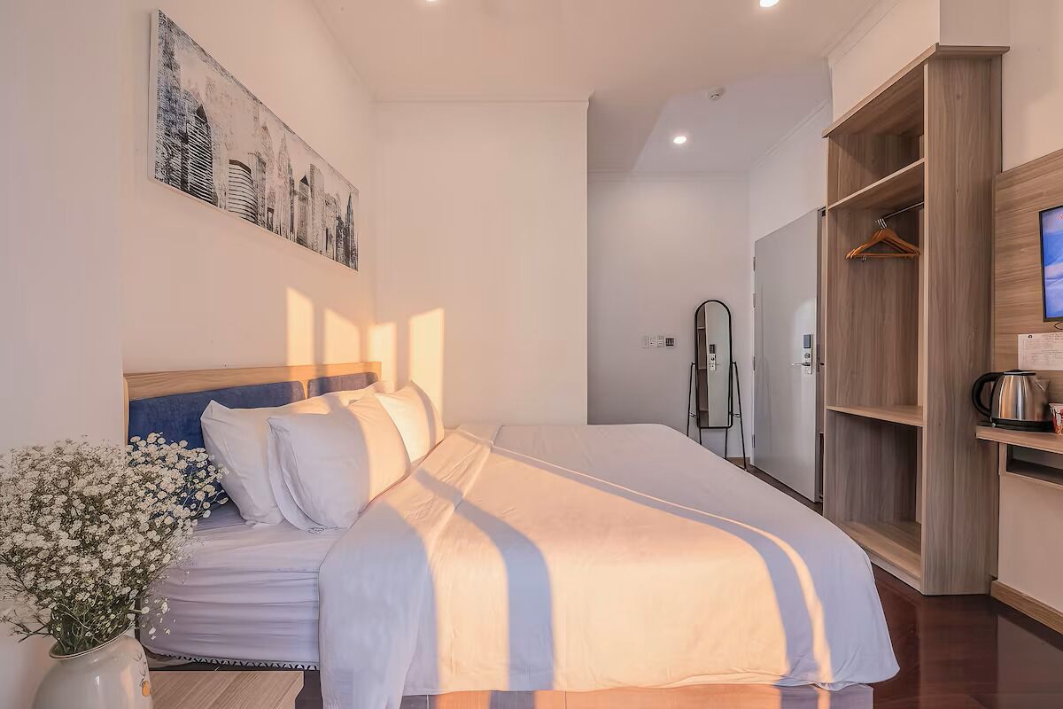 A hotel room with a bed, a wardrobe, a mirror, and a painting on the wall.
