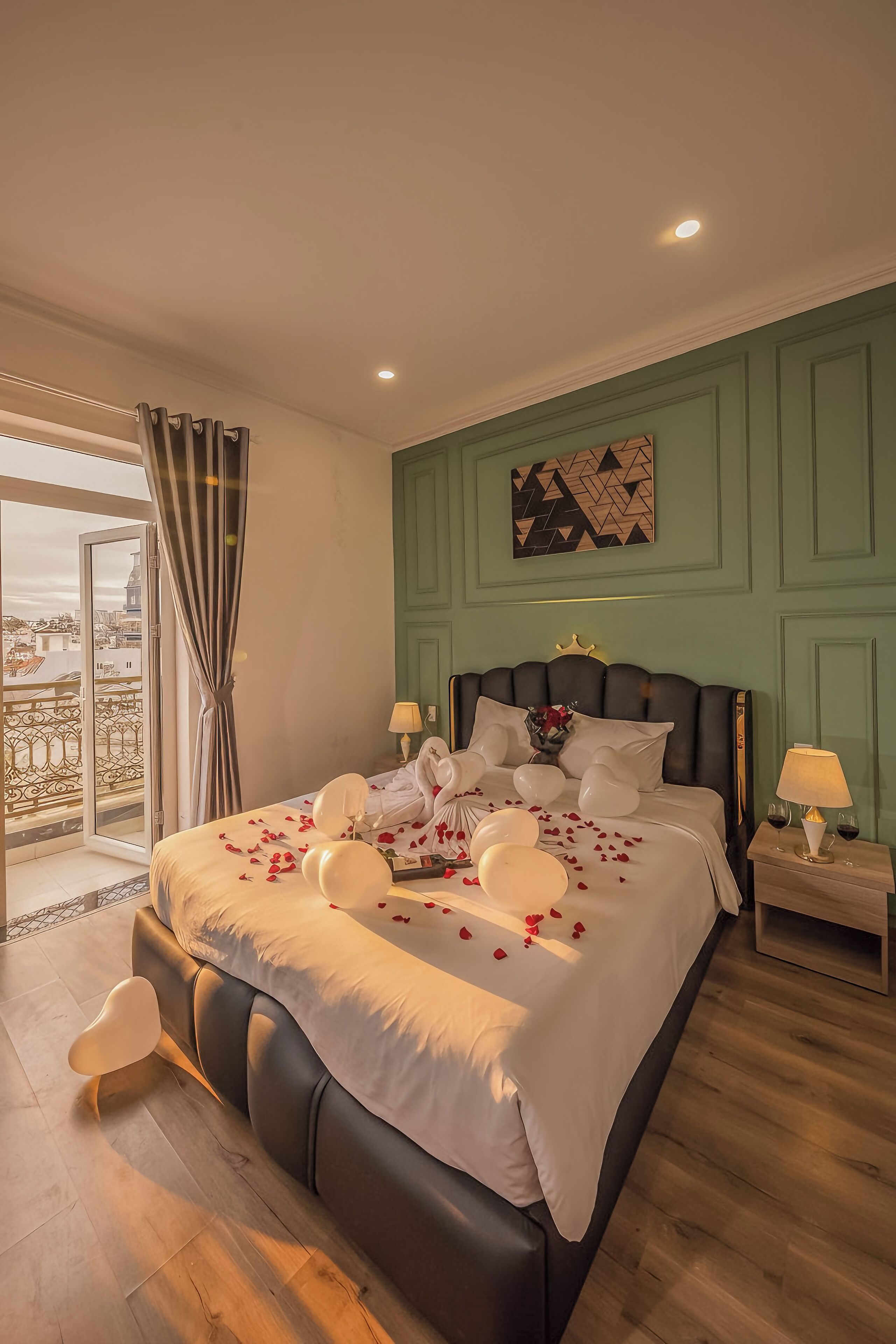Une chambre spacieuse avec un grand lit, un balcon offrant une belle vue et un mur végétal agrémenté d’une peinture aux motifs géométriques.