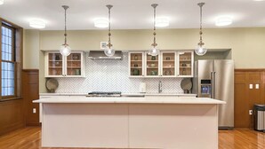 Une cuisine moderne dotée d’un îlot central, de luminaires suspendus et d’armoires encastrées.