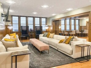A spacious living room with a large window, a sofa set, a coffee table, and a dining area with chairs. - Downtown Oasis: Steps to Dining & Sights. Pool + Gym in Building (Cleveland)
