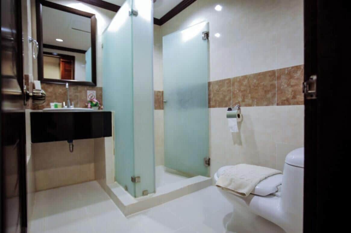 Un baño con ducha de vidrio, inodoro blanco y lavamanos con espejo.