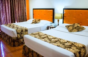 Dos camas individuales con cabeceras naranjas, ropa blanca de cama y correpasillos estampados con motivos florales.