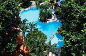 An aerial view of a swimming pool surrounded by lush greenery and palm trees.
