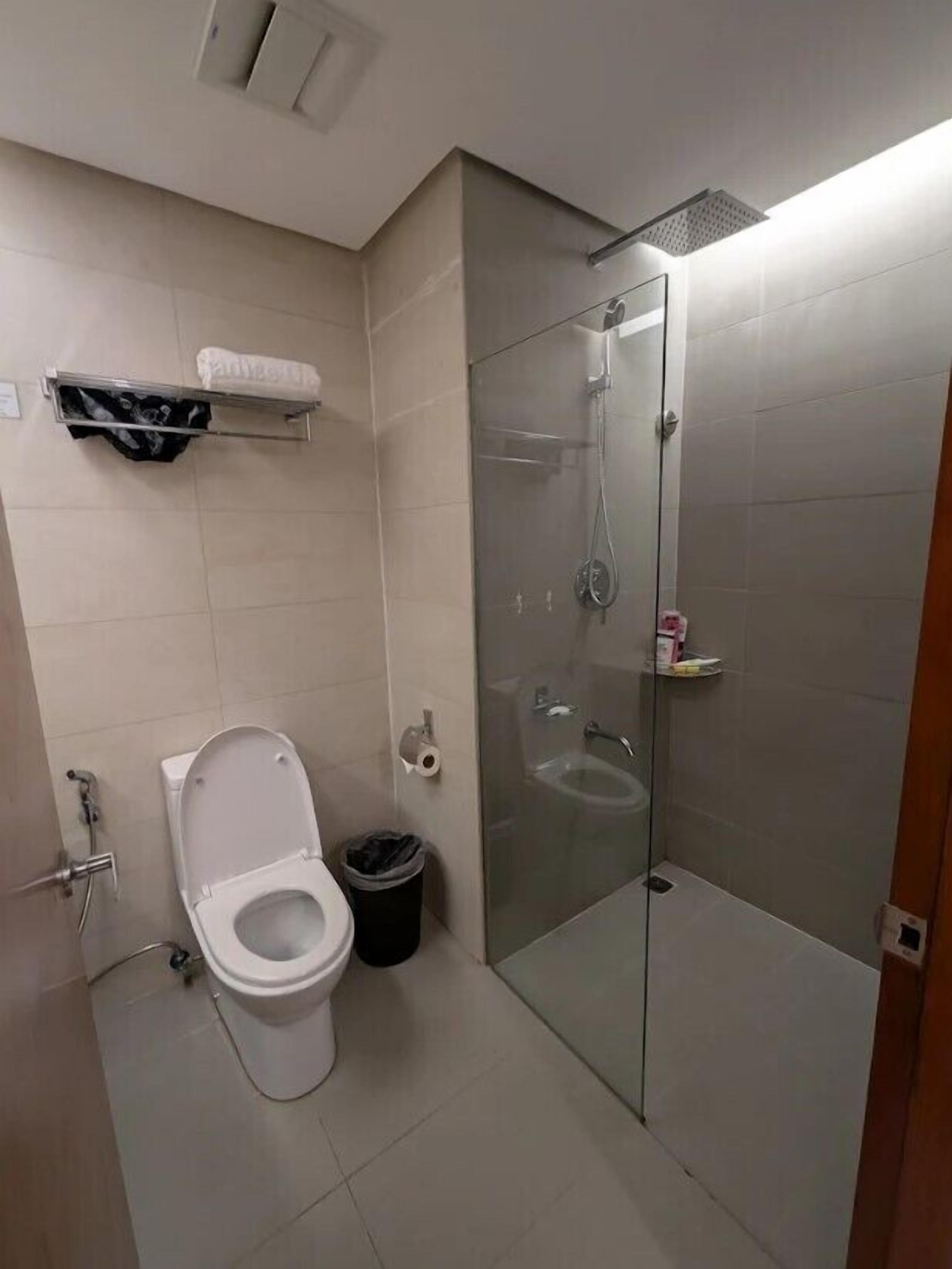 Une salle de bain moderne équipée de toilettes, d’une douche à parois de verre et d’un porte-serviettes.