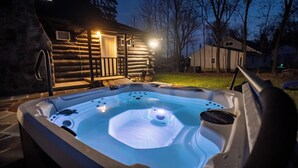 A hot tub in a backyard with a wooden cabin in the background. - Timber Lodge: Hot Tub, Fireplace & Fun for All ! (West Milford)