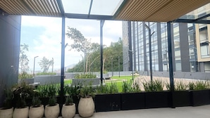 A modern building with a glass facade, outdoor seating area, and potted plants. - Despierta con vista a la montaña (Bogotá)