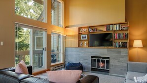 Una sala de estar moderna con chimenea, estanterías, un sofá de cuero y un televisor de pantalla plana.