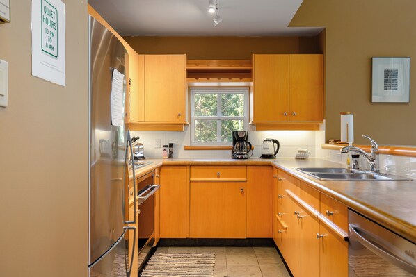 Una cocina moderna con armarios de madera, electrodomésticos de acero inoxidable y un ventanal que proporciona luz natural.