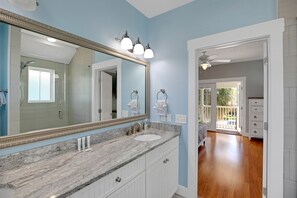A bathroom with a marble sink, a large mirror, and a ceiling fan.