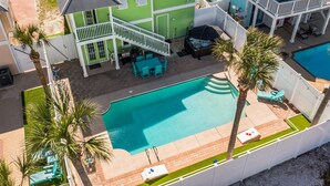 An aerial view of a property with a swimming pool, a covered patio, and a two-story building with a green exterior. - Steps2Beach~Heated Pool~MiniGolf~Hot Tub~Game Room (Panama city)
