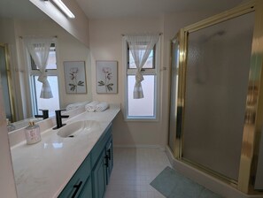 Un bagno con un grande specchio, due lavandini, una vasca da bagno e una zona doccia.