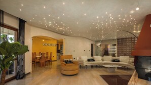 A spacious living area with a curved ceiling, a dining area, and a modern fireplace.