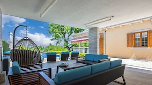 An outdoor patio with a seating area, including a sofa and chairs, and a hanging light fixture.
