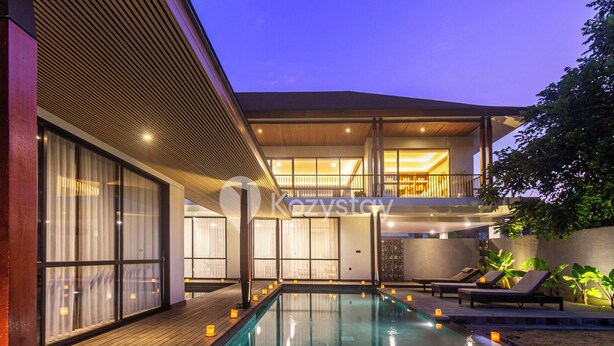 Ein moderner Poolbereich mit Holzterrasse, Liegestühlen und klarem Wasser.