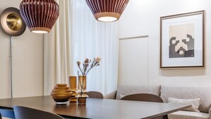 Een moderne eetruimte met een houten tafel, zwarte stoelen en een bank. Er staan decoratieve vazen en een lijst met een afbeelding aan de muur.
