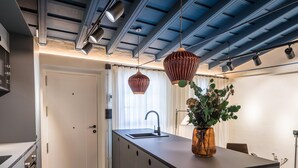 A modern kitchen with a central island, pendant lighting, and a vase with flowers.