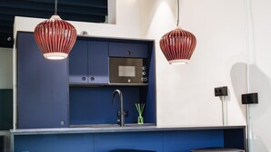 Una cocina moderna con armarios azules, un lavamanos de acero inoxidable y dos taburetes negros.