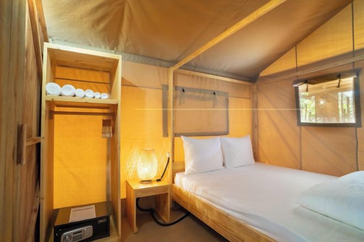 Una habitación acogedora de madera con una cama, una mesita de noche con lámpara y un estante con artículos de tocador.