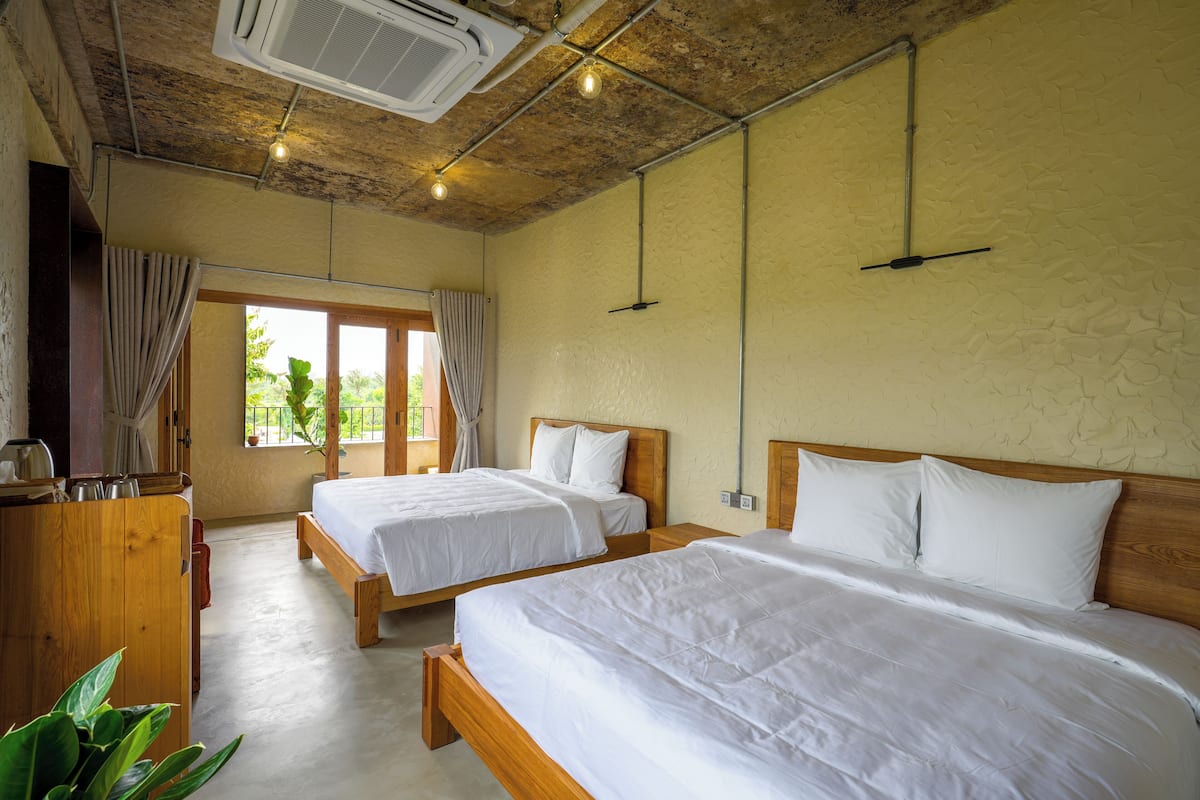 Habitación de hotel con dos camas individuales, cabeceros de madera y un armario de madera.