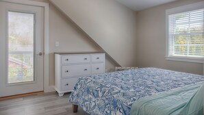 Un dormitorio con cama, cómoda, ventana y puerta.
