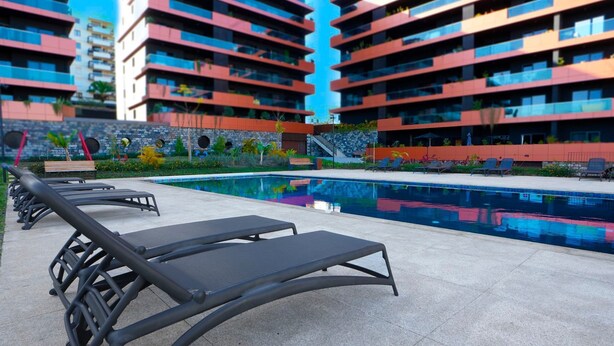 A modern hotel with a swimming pool, sun loungers, and a stone wall with circular cutouts. - Diamond Ocean View by LovelyStay (Funchal)