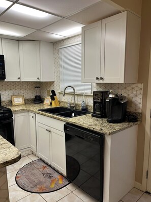 Kitchen area with dishwasher, coffee maker, and sink.