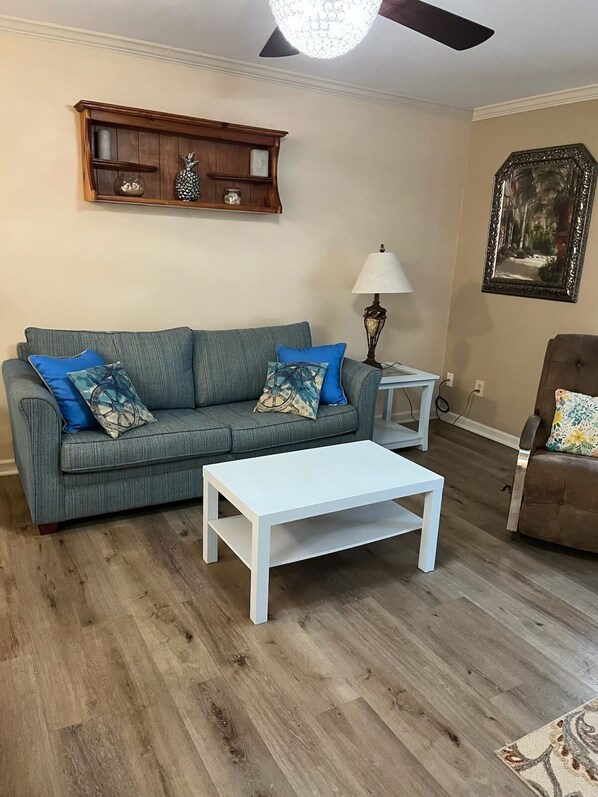 Relax in this inviting living room with a sofa, coffee table, and ceiling fan.
