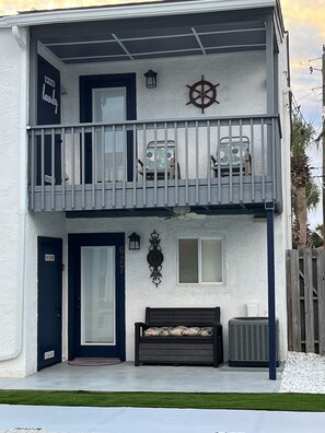 Two-story residence with a balcony featuring a railing, two chairs, and a table.