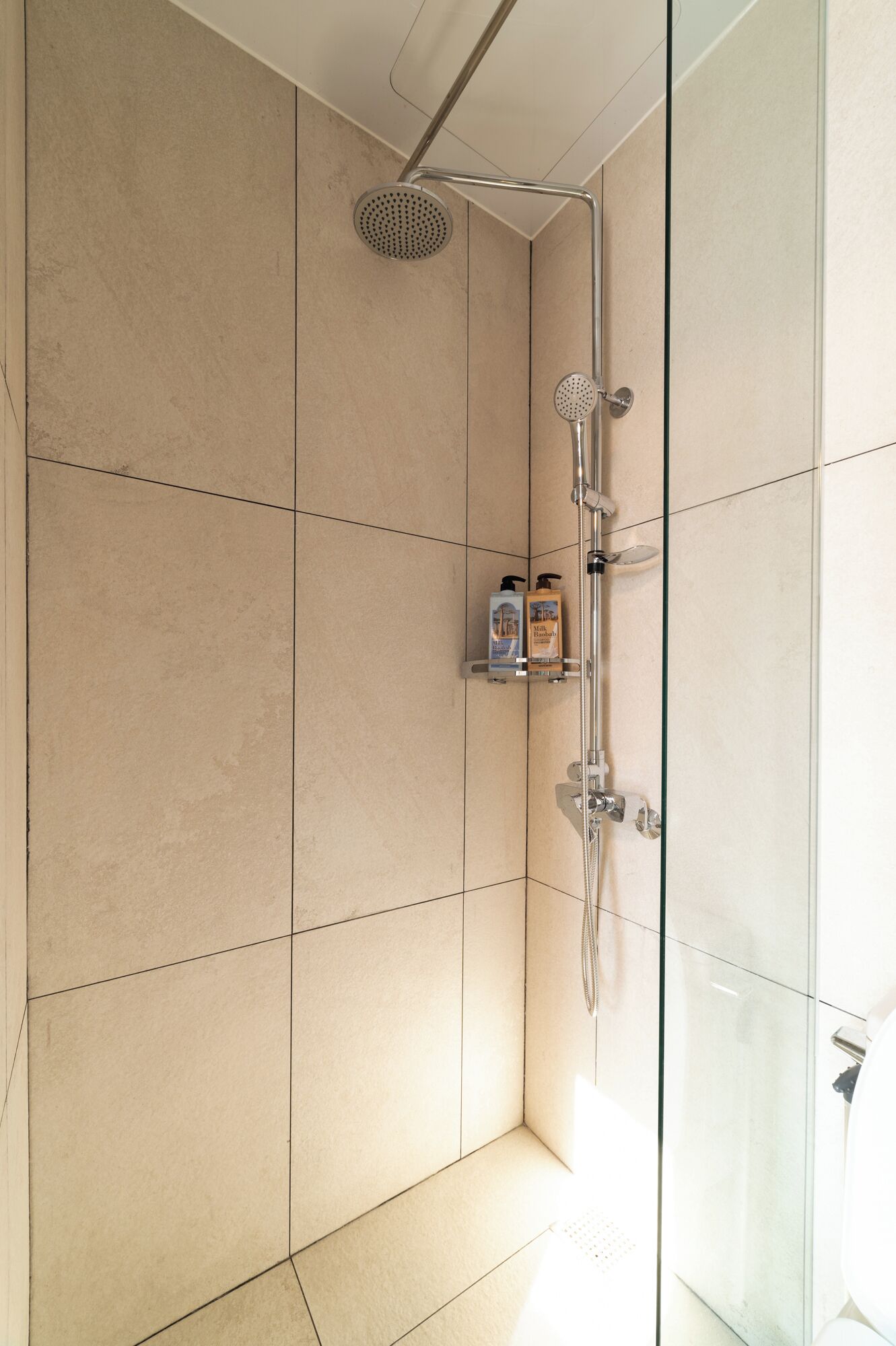 A modern shower with a handheld showerhead and a fixed rain showerhead.