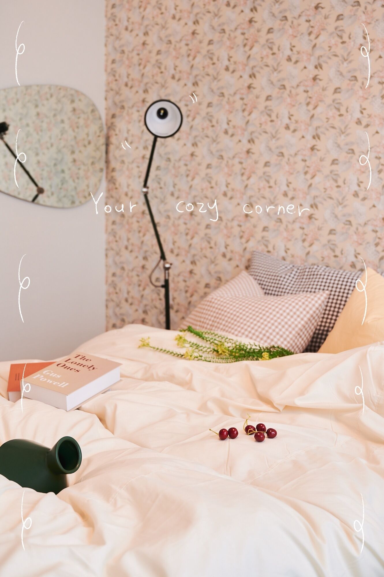 Ein gemütliches Schlafzimmer mit floraler Tapete, einem karierten Kopfkissen und einer Lampe in Augenform als Dekoration. Auf dem Nachttisch liegt ein Buch mit dem Titel 'The Lonely Ones'.