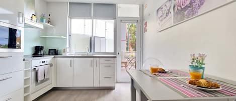 A modern kitchen with white cabinets, a coffee maker, and a dining area with a table set for breakfast.