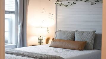 Ein Schlafzimmer mit Bett, Deckenventilator, Fenster mit Vorhängen und Wand mit Dekorationselementen.