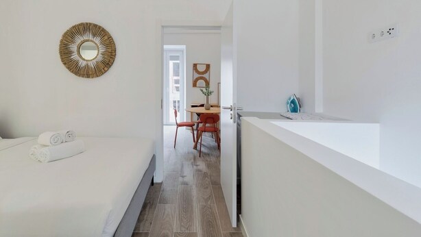 Habitació d'hotel moderna amb un llit, un petit escriptori, una cadira i un bany amb un lavabo.