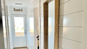 A hallway with white paneled walls, a wooden floor, and a door with a nameplate. - Cabell’s Coastal Cottage-Sleeps 10 Jockey’s Ridge 1 mile to beach Sunsets & Pets (Nags Head)