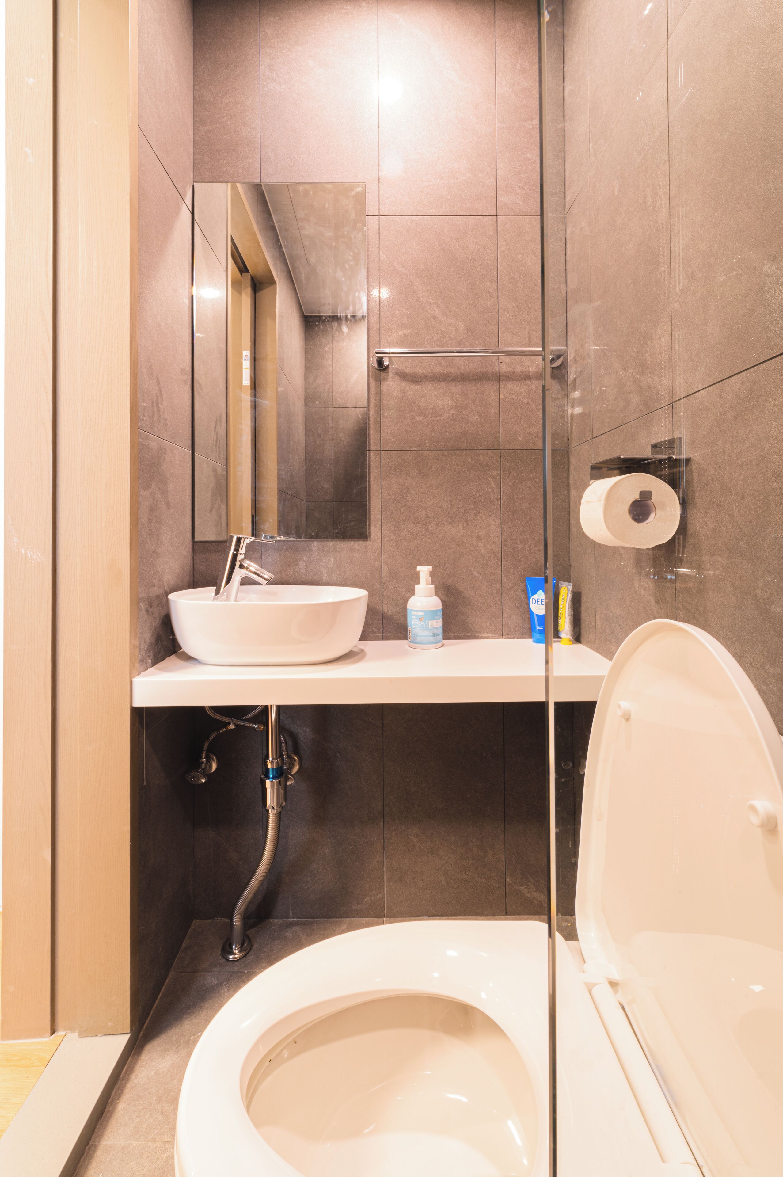 A modern bathroom with a white sink, a mirror, a toilet, and a shower area.