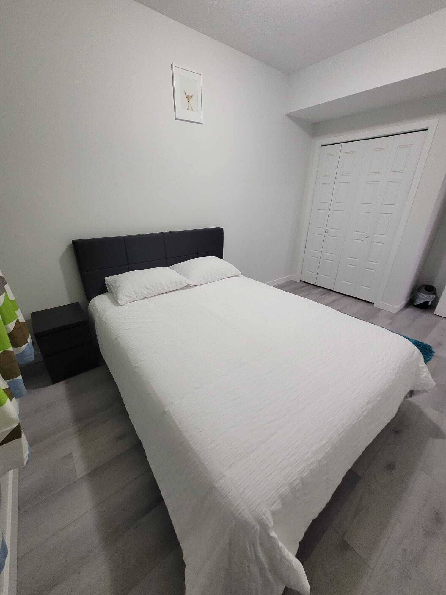 Une chambre à coucher avec un lit, une table de chevet, une armoire et un tableau encadré au mur.
